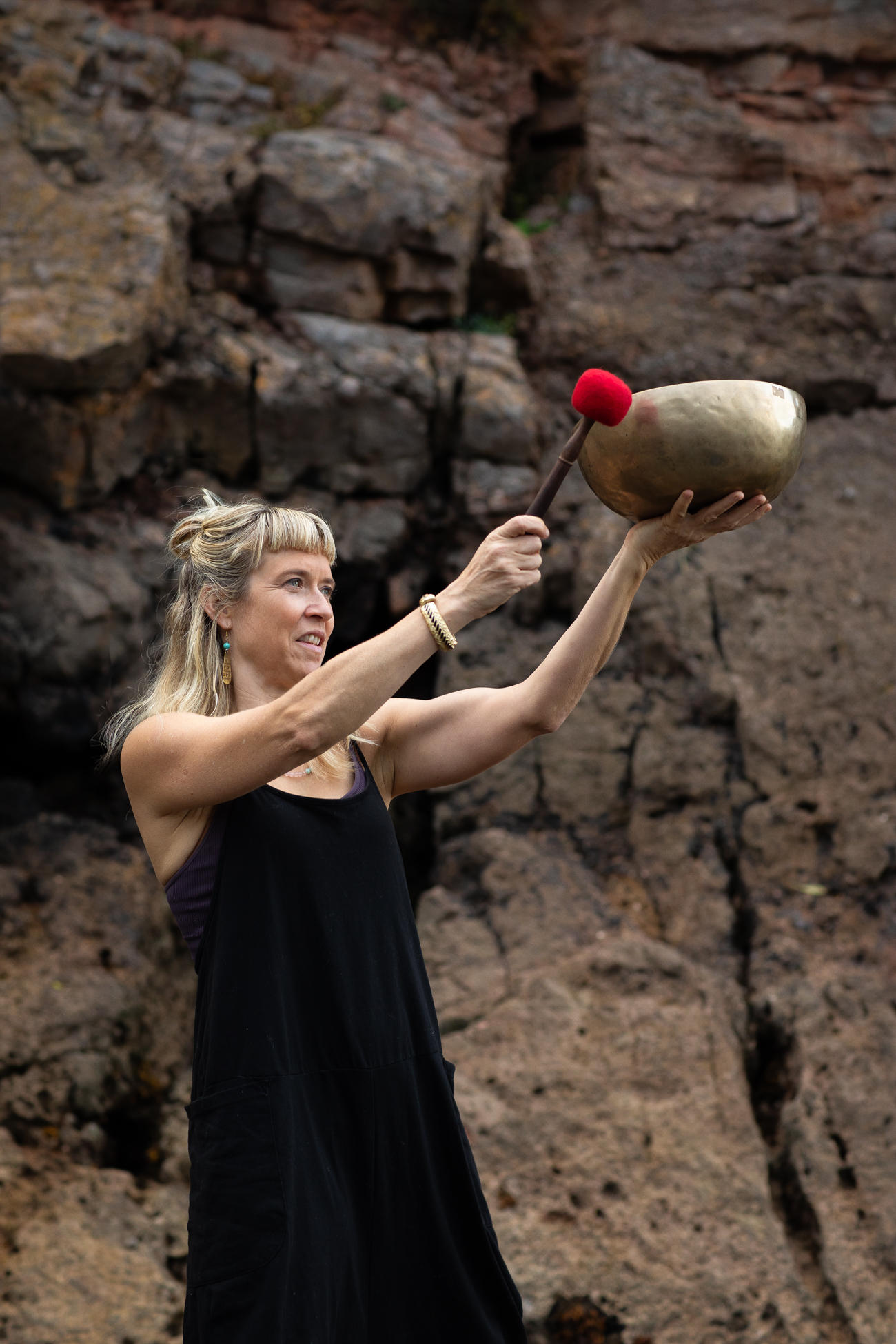 Gina with singing bowl on rocks